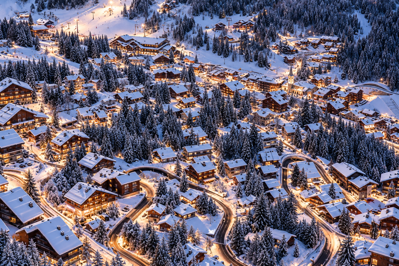 Aerial view of a snow-covered Alpine village with traditional chalets, hotels and warm festive lights, illustrating Christmas ski holidays in Méribel.
